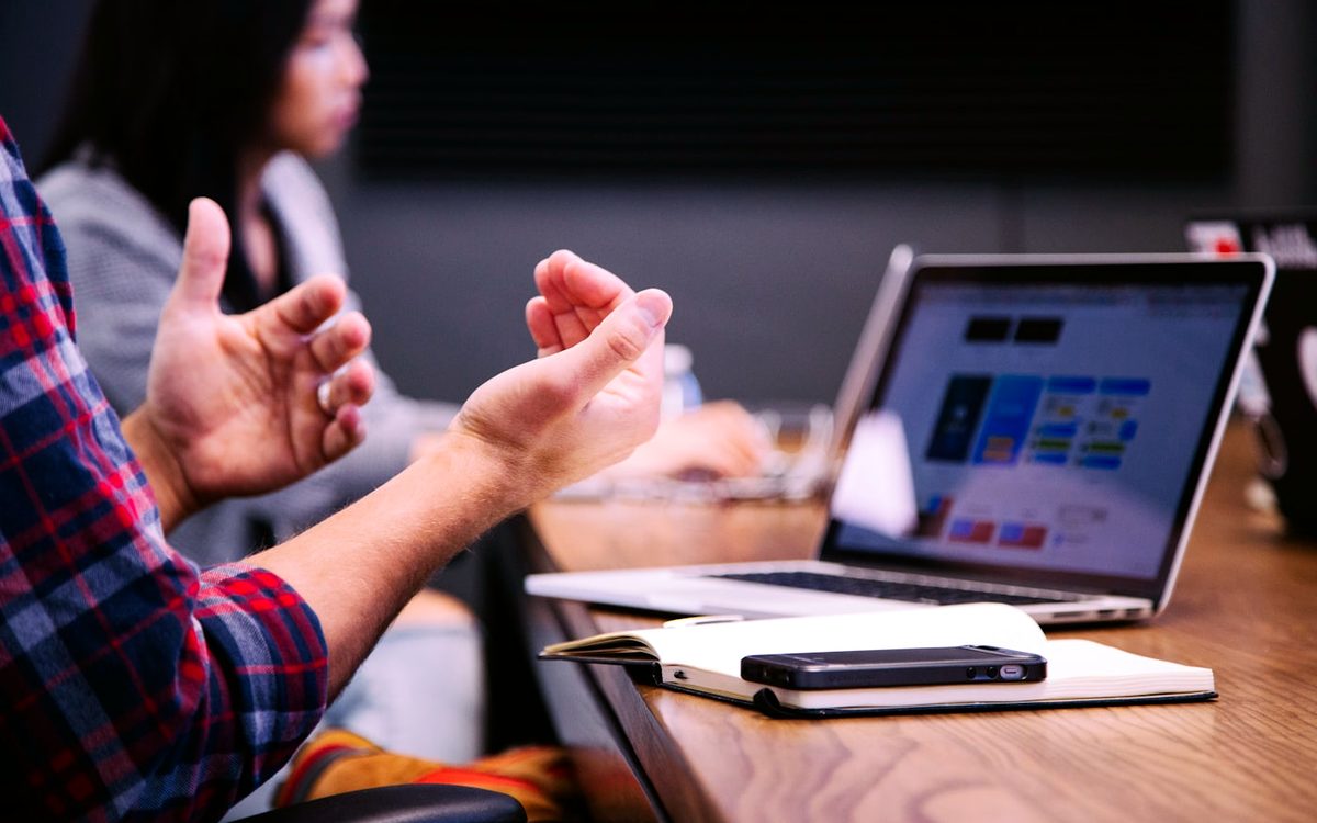 Twee mensen die pratend over een laptop gebogen staan tijdens een werkoverleg